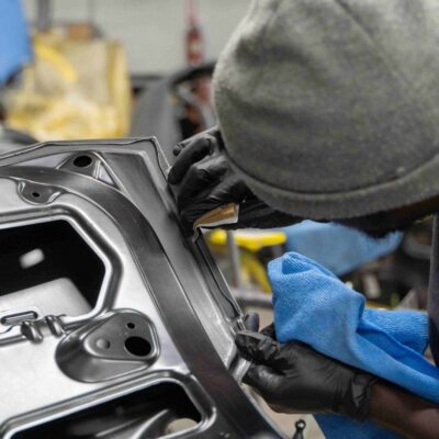 Technician working on detailed car door components with precision tools