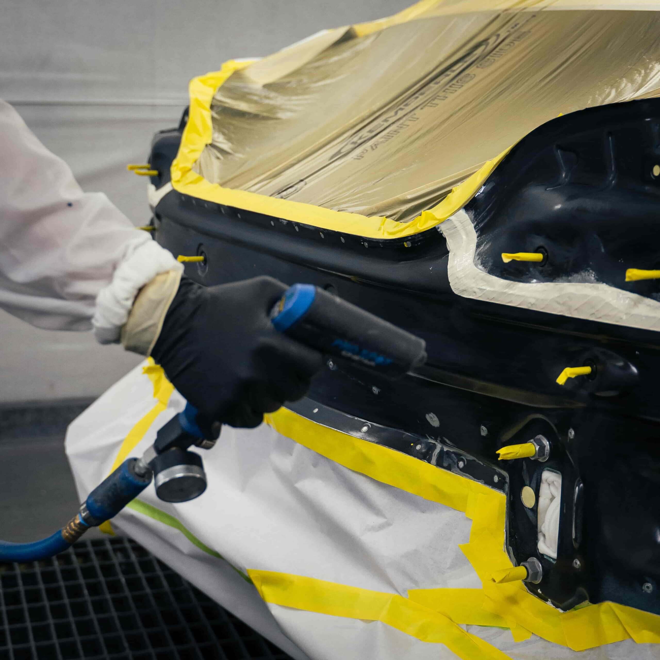 A car covered with a yellow tarp in a repair shop.